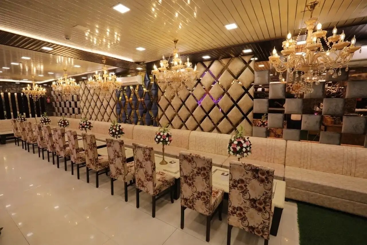 Luxury banquet hall interior with elegant chandelier lighting, long dining table setup, and floral centerpieces for wedding or events.