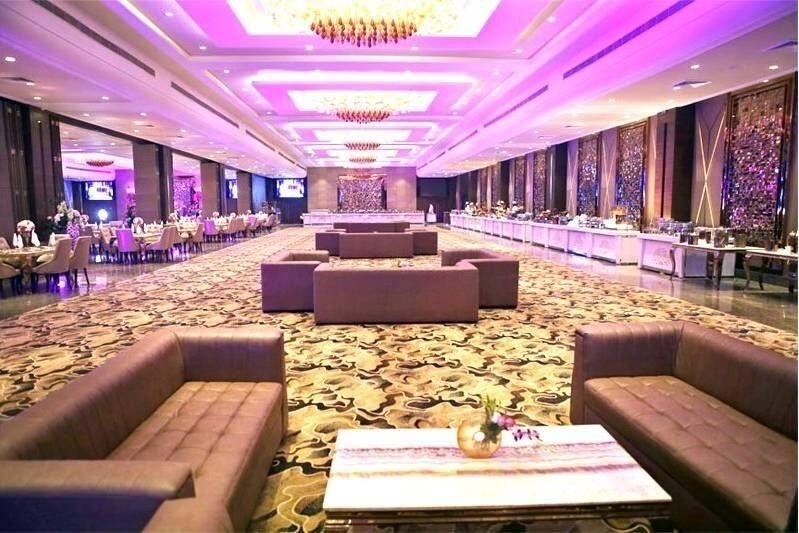 Large luxury banquet hall with purple ambient lighting, buffet counters along the sides, lounge seating in the center.