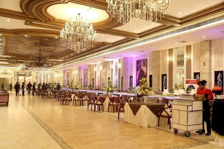 Elegant banquet hall with buffet arrangement, chandelier lighting, and large seating area ideal for weddings and corporate events.